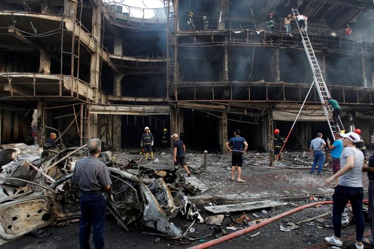 © Reuters. People gather at the site of a suicide car bomb in the Karrada shopping area, in Baghdad, Iraq