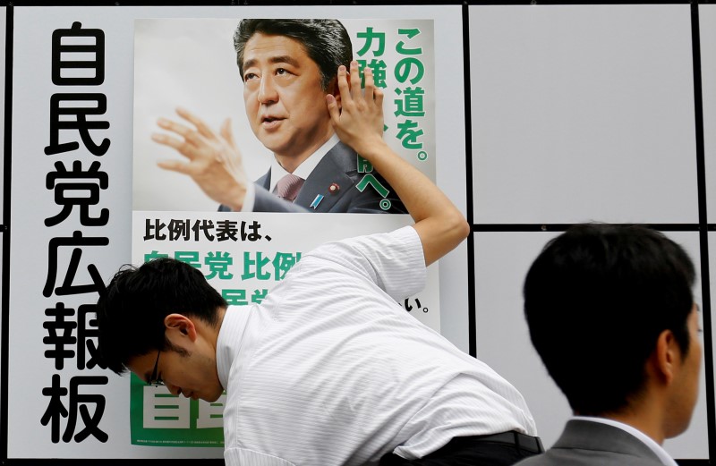 © Reuters. A staff member of Japan's ruling Liberal Democratic Party (LDP) posts a poster for the July 10 upper house election with the image of Shinzo Abe, Japan's Prime Minister and leader of the LDP, at the LDP headquarters in Tokyo