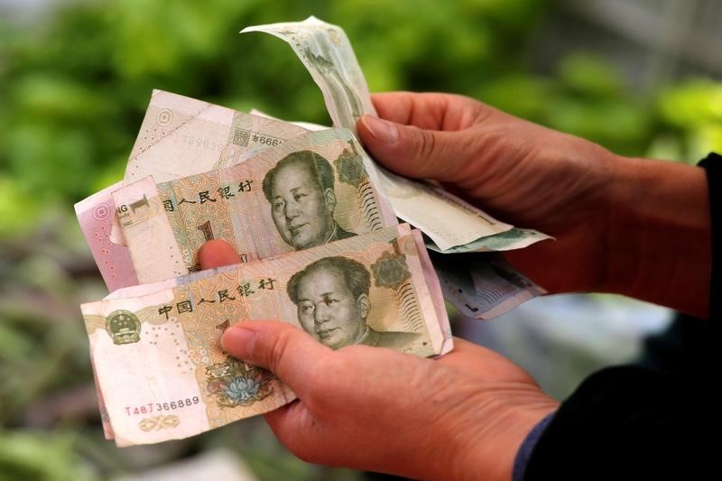 © Reuters. A customer counts Chinese yuan banknotes as she purchases vegetables at a market in Beijing