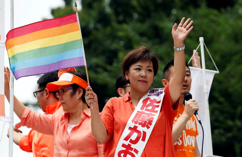 © Reuters. Sato, independent candidate running for the upcoming upper house election, holding a rainbow flag, wave as Taniyama, gay supporter of Sato from Nakano LGBT Network Nijiiro, speaks during a campaign for the July 10 upper house election in Tokyo
