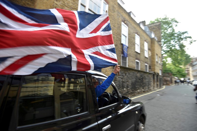 © Reuters. A taxi driver holds a Union flag, as he celebrates following the result of the EU referendum, in central London