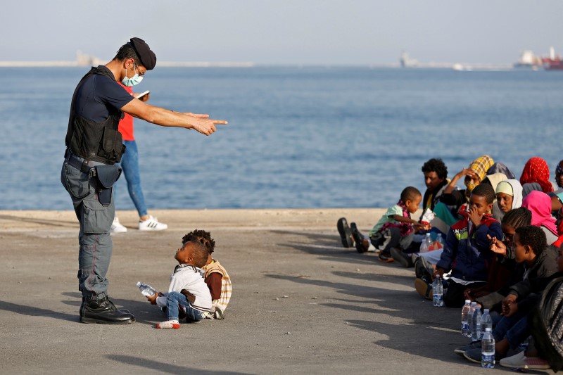 © Reuters. Policial conversando com crianças imigrantes no porto de Augusta, na Itália