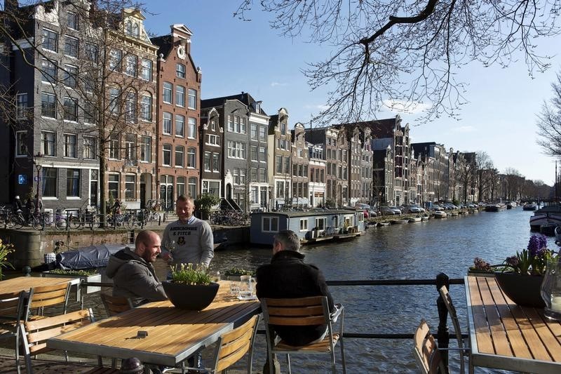 © Reuters. Men enjoy the afternoon sun at the Brouwersgracht canal in Amsterdam