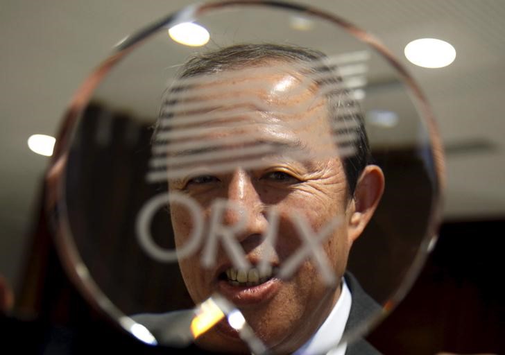 © Reuters. Orix Corp CEO Inoue poses behind the company logo after an interview with Reuters in Tokyo