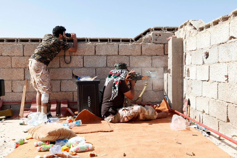 © Reuters. A sniper from forces aligned with Libya's new unity government shoots while his comrade uses binoculars to scan the area looking for an Islamic State position in Sirte