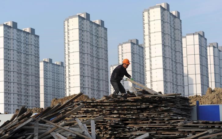 © Reuters. A labourer selects wooden planks as he works at a residential construction site in Hefei
