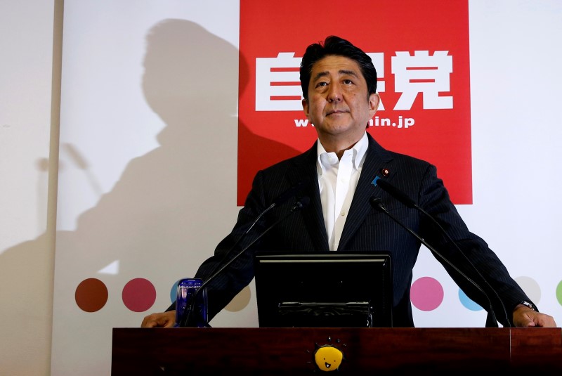 © Reuters. Japan's PM and leader of the ruling LDP Abe poses for photos before a news conference following a victory in upper house elections by his ruling coalition in Tokyo