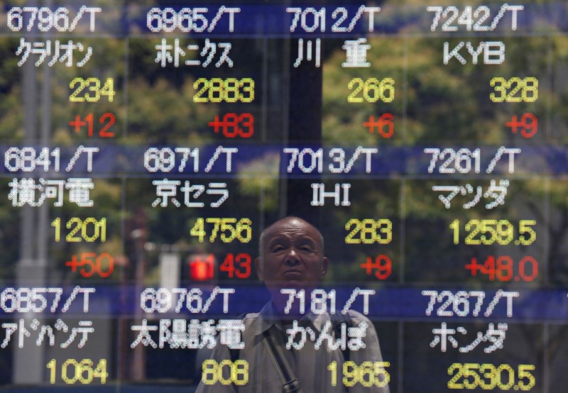 © Reuters. A man is reflected on a stock quotation board outside a brokerage in Tokyo, Japan