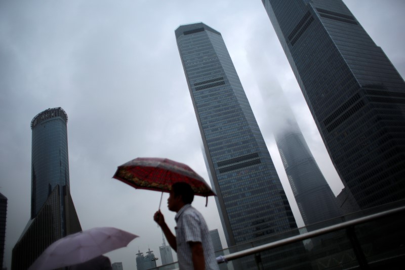 © Reuters. A man walks in the rain along the financial district of Pudong in downtown Shanghai