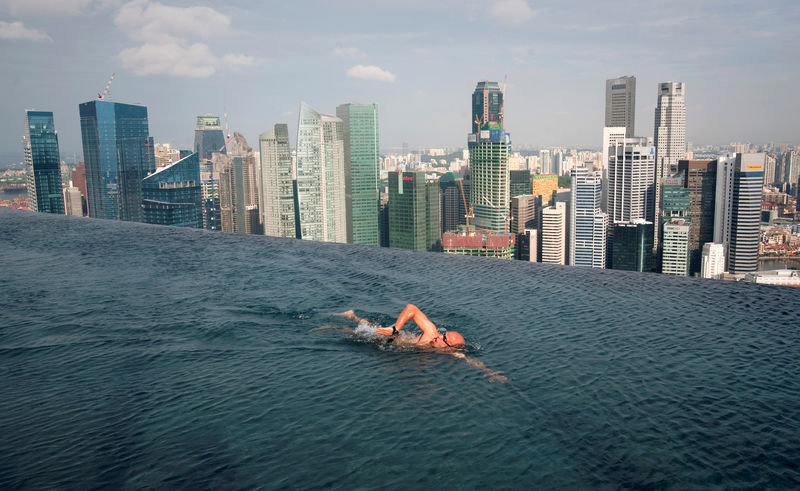 © Reuters. A guest swims in the infinity pool of the Skypark that tops the Marina Bay Sands hotel towers in Singapore