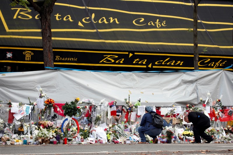 © Reuters. People mourn in front of the screened-off facade of the Bataclan Cafe adjoining the concert hall, one of the sites of the deadly attacks in Paris