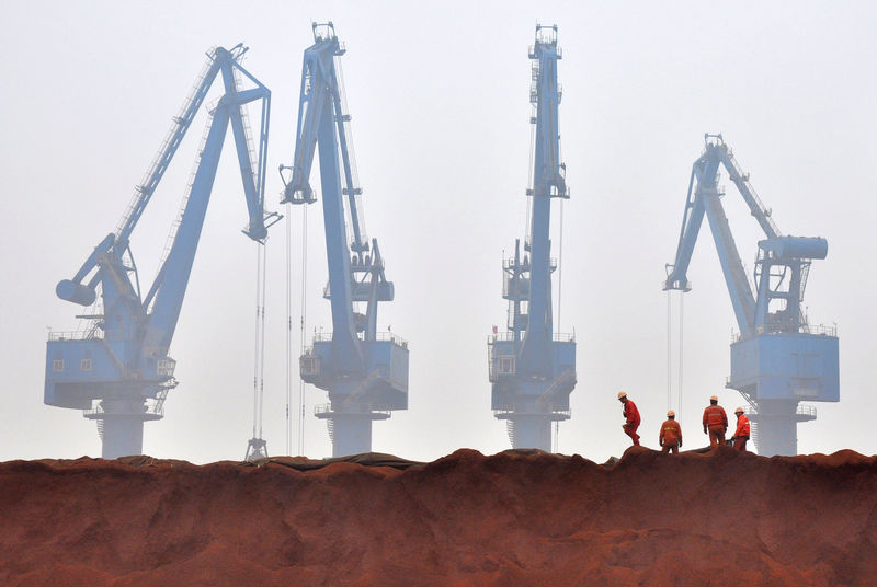 © Reuters. Workers remove the cloth covering the iron ore from Australia while they prepare for transporting at a port in Tianjin municipality