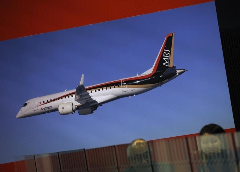 © Reuters. Employees sit at the Mitsubishi Regional Jet booth during the opening day of the Singapore Airshow at Changi Exhibition Center