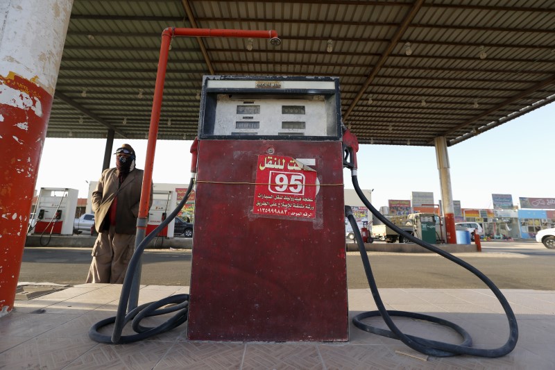 © Reuters. A fuel pump assistant stands next to an old fuel pump during the early hours near the village of Salwa at the Qatari-Saudi border, south of the eastern provience of Khobar