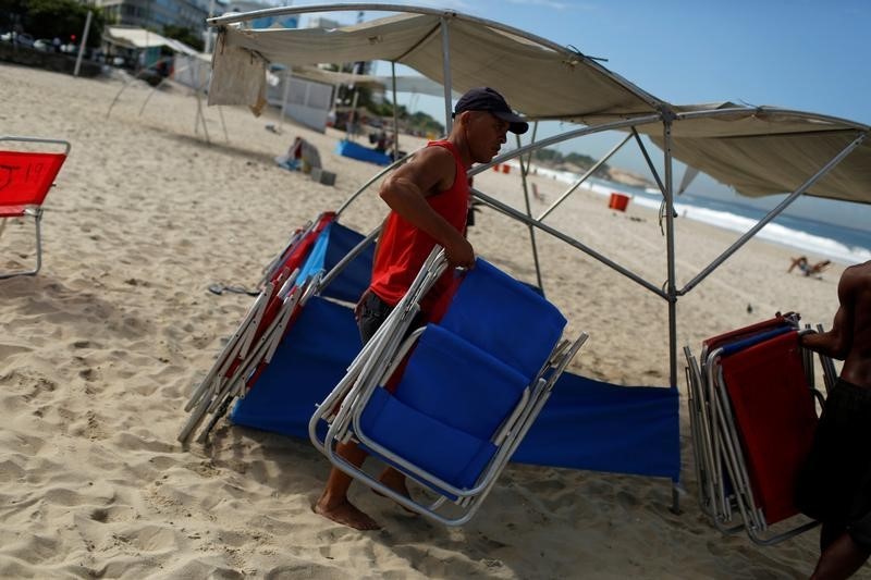 © Reuters. Man carries chairs to be rented to visitors at Ipanema beach in Rio de Janeiro
