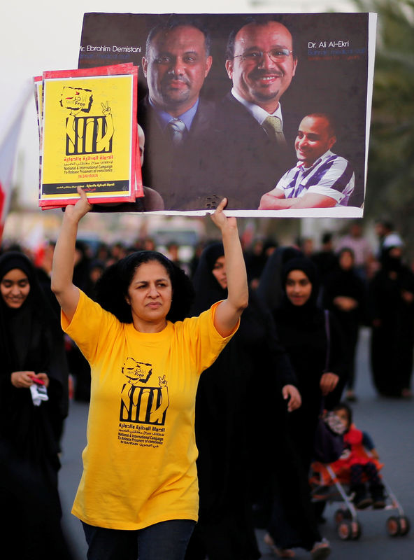 © Reuters. A senior nurse Rula al-Saffar holds a banner with photos of Dr Ali al-Ekri and Ebrahim Demistani as she participates in an anti-government rally organized by Bahrain's main opposition party Al Wefaq in Budaiya, west of Manama