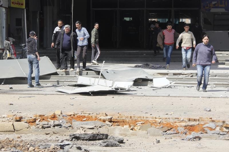 © Reuters. Civilians rush out of a building after airstrikes in the northwestern Homs district of Al Waer