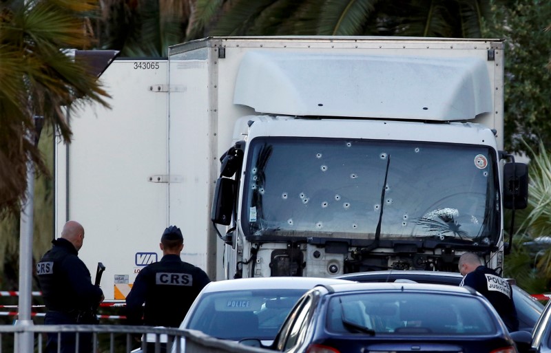 © Reuters. French CRS and judicial police work near the heavy truck that ran into a crowd at high speed celebrating the Bastille Day July 14 national holiday on the Promenade des Anglais killing 80 people in Nice