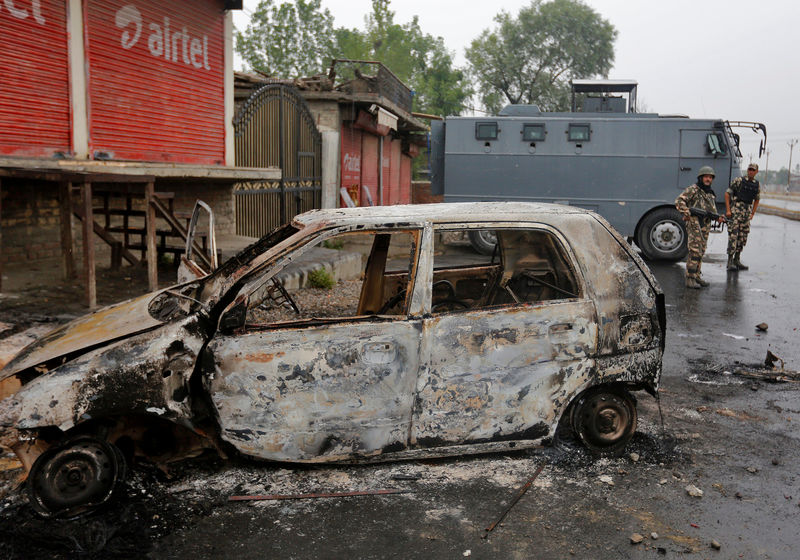 © Reuters. Indian policemen stand guard next to the wreckage of a vehicle that was damaged during a protest on Thursday evening, during a curfew in Srinagar