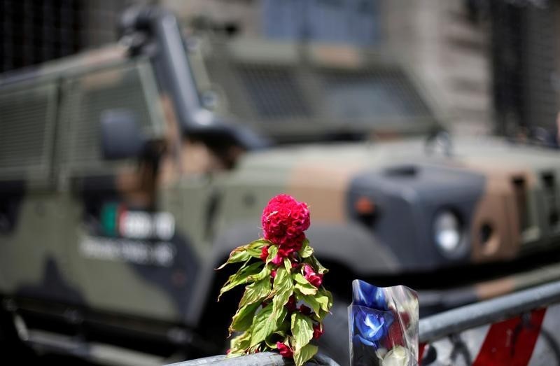 © Reuters. Flowers placed to pay tribute to the victims of the Bastille Day truck attack in Nice are seen in front of a military armoured vehicle at the French embassy in Rome