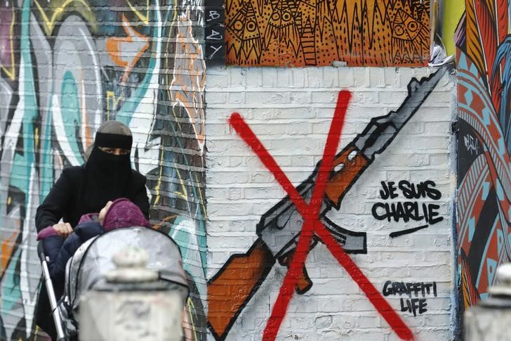 © Reuters. Женщина с коляской у граффити "Je Suis Charlie" в Лондоне