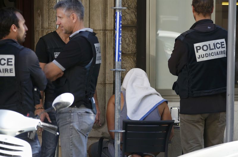 © Reuters. A man covered with a towel is apprehended by French police as the investigation continues two days after an attack by the driver of a heavy truck who ran into a crowd killing scores and injuring as many on the Promenade des Anglais, in Nice