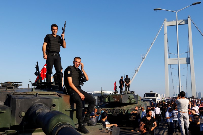 © Reuters. Policemen stand atop military armored vehicles after troops involved in the coup surrendered on the Bosphorus Bridge in Istanbul