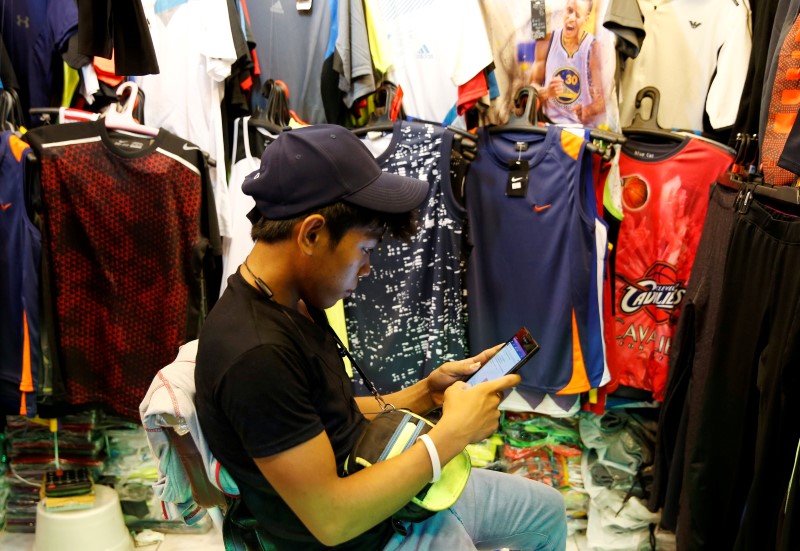 © Reuters. A vendor uses a mobile phone to surf internet at a clothes shop in Paranaque, Metro Manila