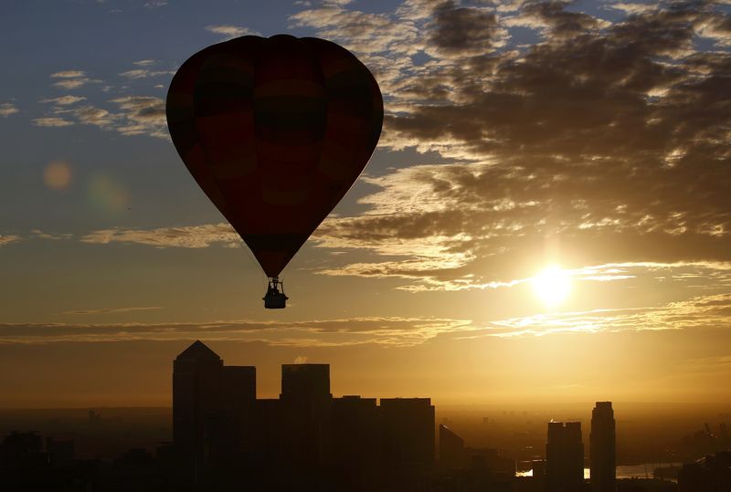 © Reuters. A hot air balloon rises into the early morning sky in front of the Canary Wharf financial district of London