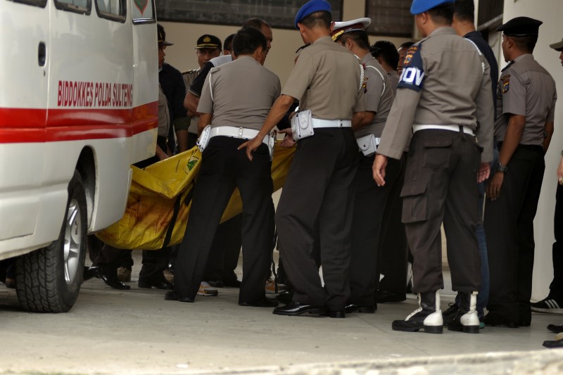 © Reuters. Police carry body bags one of which is believed to contain the remains of the country's most-wanted militant Santoso at a hospital in Palu