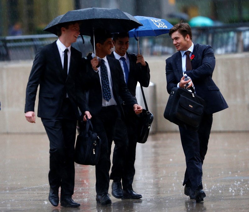 © Reuters. Workers walk in the rain at the Canary Wharf business district in London