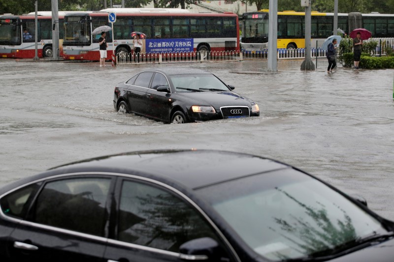 © Reuters. Cars go through a flooded street during a heavy rainfall in Shilipu, Chaoyang Road, Beijing