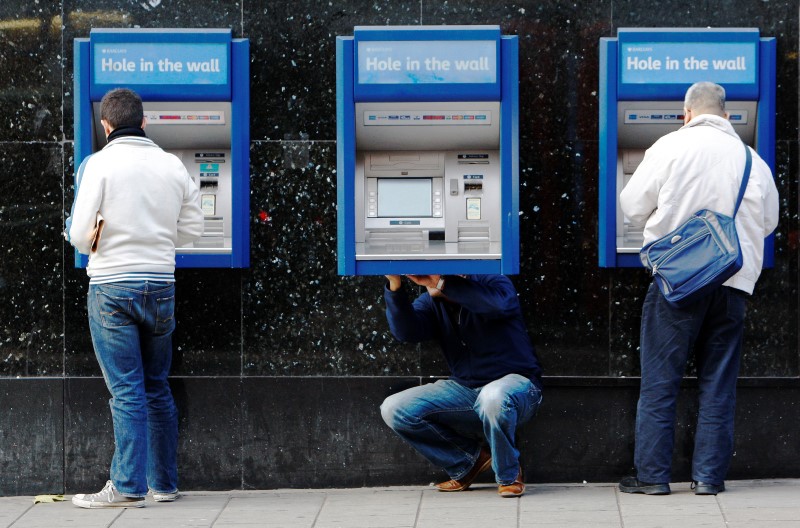 © Reuters. A man repairs a cash machine outside a bank in London