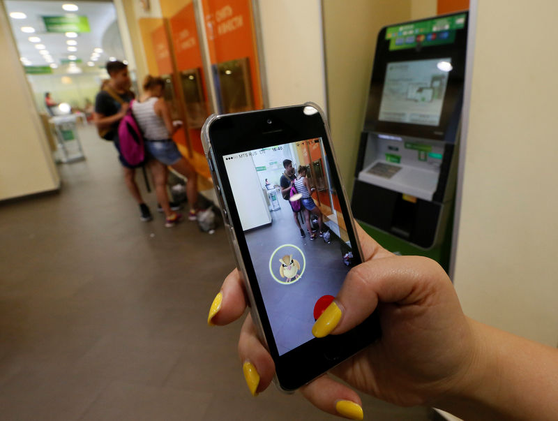 © Reuters. Woman plays augmented reality mobile game "Pokemon Go" by Nintendo at branch of Sberbank in central Krasnoyarsk