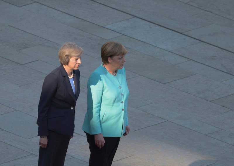 © Reuters. German Chancellor Merkel and Britain's Prime Minister May review honour guard in Berlin