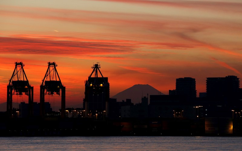 © Reuters. Mt. Fuji is seen between cranes and buildings during sunset at a port in Tokyo