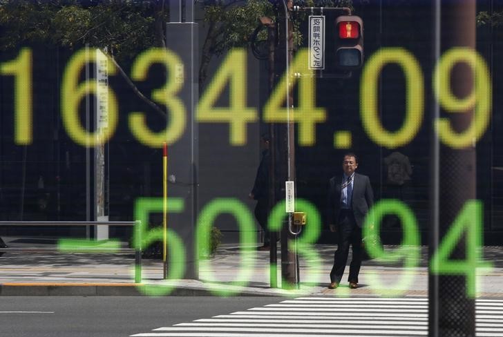 © Reuters. Businessman is reflected in an electronic board displaying Japan's Nikkei share average outside a brokerage in Tokyo