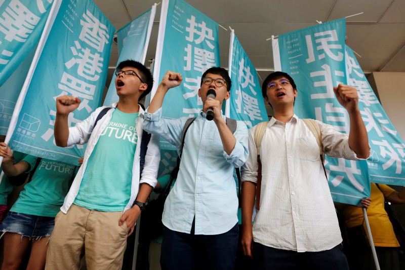 © Reuters. Student leaders Joshua Wong, Nathan Law and Alex Chow chant slogans before a verdict outside a court in Hong Kong