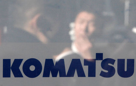 © Reuters. A man is reflected on the logo of Komatsu Ltd outside the company's headquarters in Tokyo