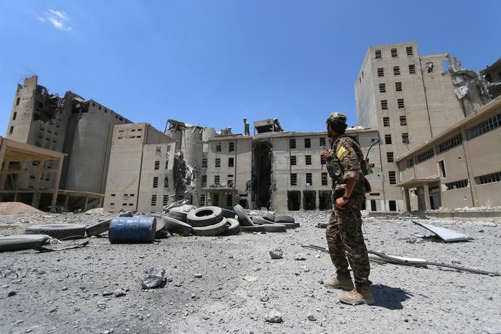 © Reuters. A Syria Democratic Forces (SDF) fighter walks along the silos and mills of Manbij after the SDF took control of it, in Aleppo Governorate