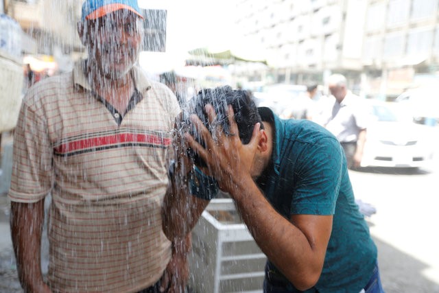 © Reuters. Homem jogando água no rosto para aliviar calor em Bagdá