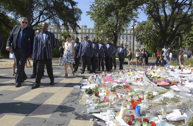 © Reuters. Michael Kenneth Wittstock, the father of Monaco's Princess Charlene, and members of the Cenestra Male Choir of South Africa pay thier respects at a makeshift memorial to the victims of the truck attack along the Promenade des Anglais in Nice