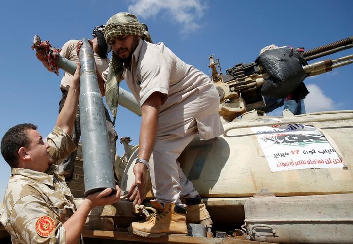 © Reuters. Fighters of Libyan forces allied with the U.N.-backed government carry a tank shell in during a battle with IS fighters in Sirte,