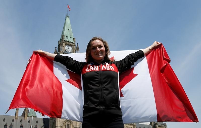© Reuters. ماكلينان لاعبة الترامبولين تحمل علم كندا في افتتاح أولمبياد ريو