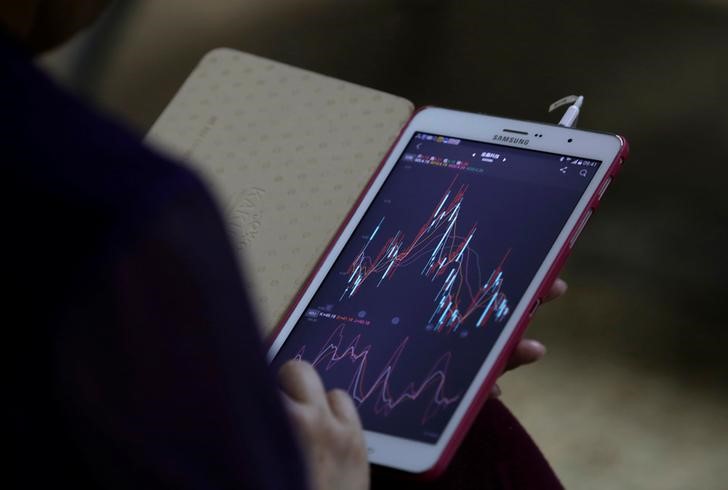 © Reuters. Инвестор проверяет фондовую информацию на своем самртфоне в брокерской компании Пекина