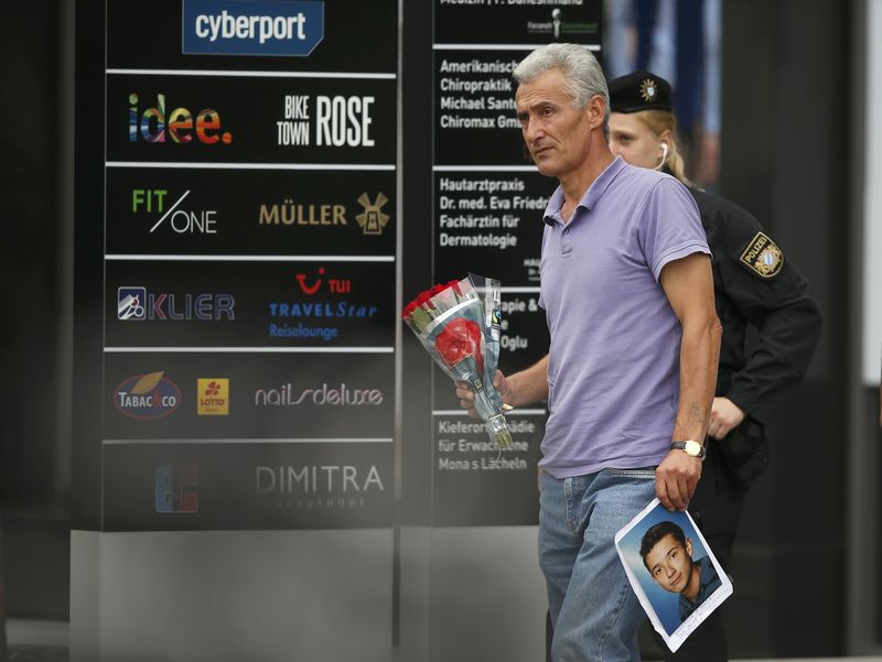 © Reuters. Man holding photo he claims is his slain son approaches police cordon near Olympia shopping mall in Munich