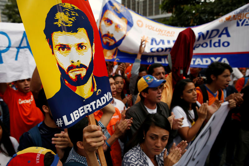 © Reuters. Supporters of jailed Venezuelan opposition leader Leopoldo Lopez, holding placards depicting him, shout slogans as they wait for his hearing at a courthouse in Caracas