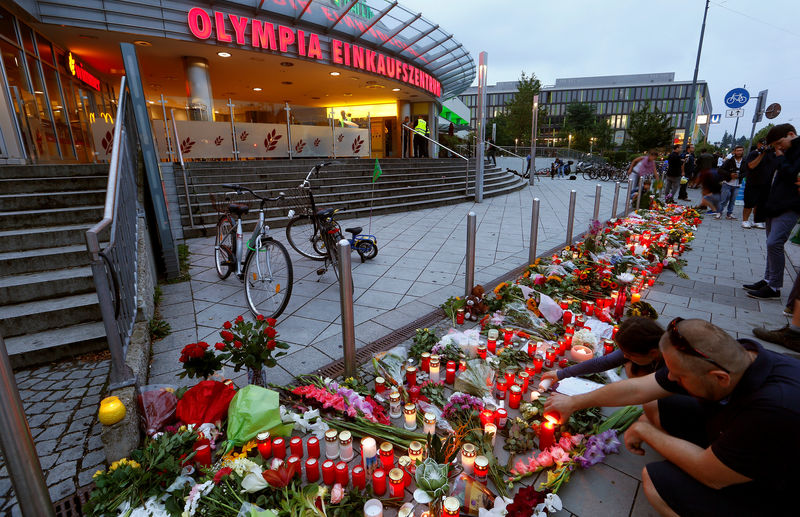 © Reuters. People light candles beside flowers laid in front of the Olympia shopping mall, where yesterday's shooting rampage started, in Munich