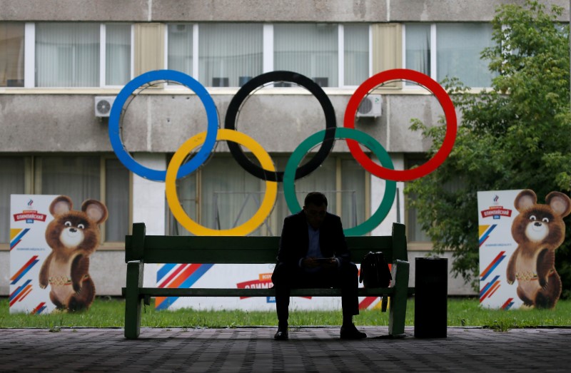 © Reuters. A man uses his tablet computer as he sits near Olympic rings placed in the courtyard of the Russian Olympic Committee headquarters in Moscow