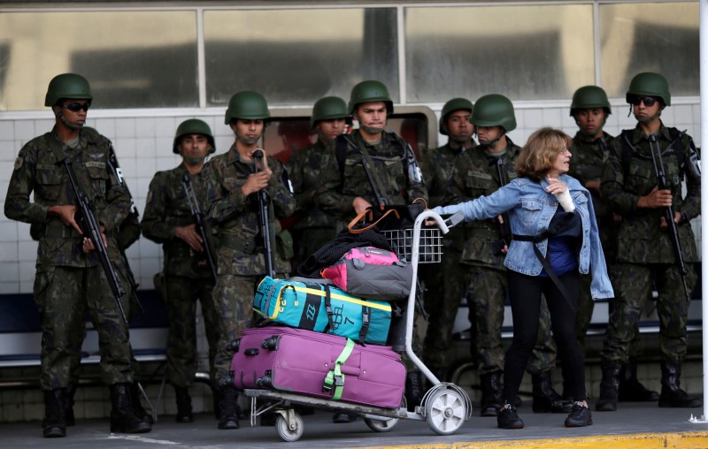 © Reuters. A passenger waits as Brazilian Air force soldiers patrol the Tom Jobim International airport in Rio de Janeiro